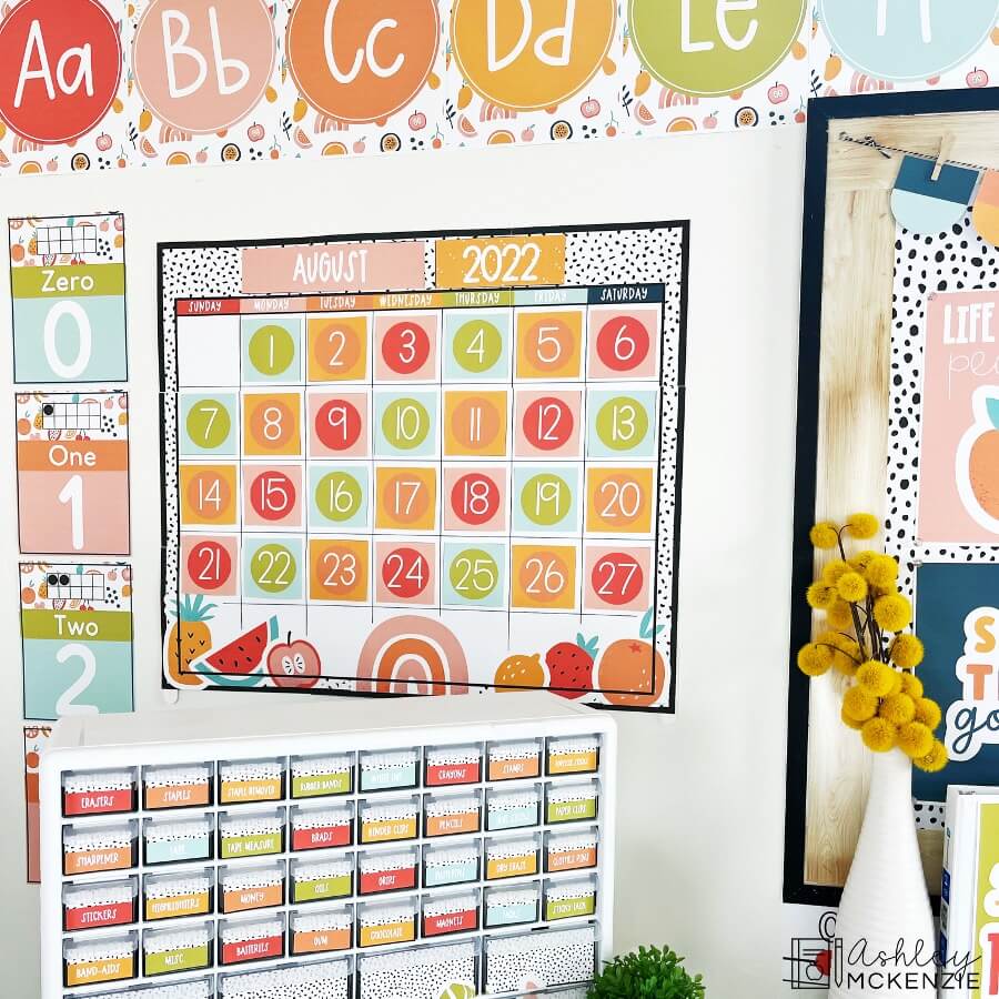 A classroom wall calendar is displayed featuring bright colors and a fruit theme. 