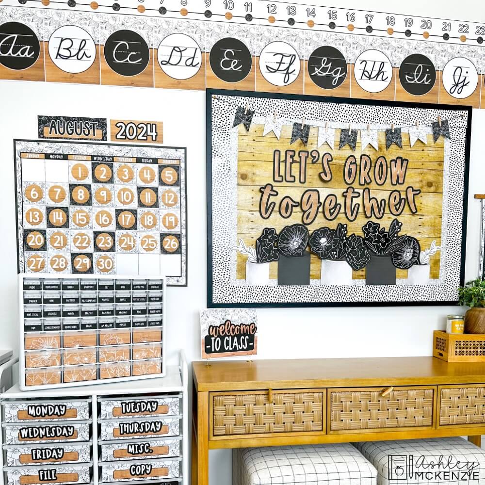 A classroom decorated with a black and white decor theme featuring delicate floral designs, including a bulletin board display, calendar kit, and alphabet posters.