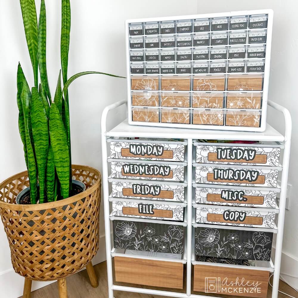 A teacher toolbox decorated with floral black and white organizing labels is displayed on top of a 12 drawer rolling cart with matching labels.