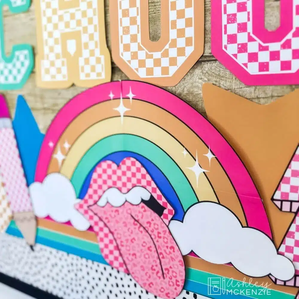 A closeup of bulletin board decor cutouts on a classroom display featuring a rainbow and retro style mouth with tongue sticking out