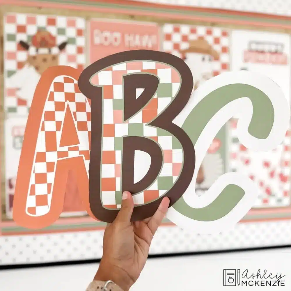 Large primary-friendly font style bulletin board letters featuring checkered patterns in front of a classroom bulletin board decorated for Halloween