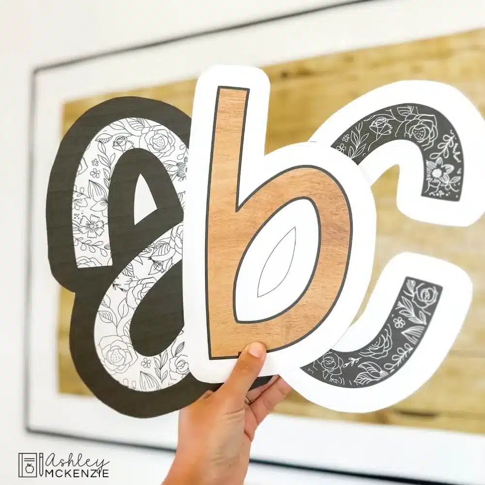 Black and white bulletin board letters are held in front of a classroom bulletin board