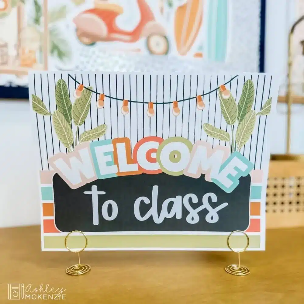 A free download of a tropical themed classroom sign that says "Welcome To Class" displayed on a table using small sign holders