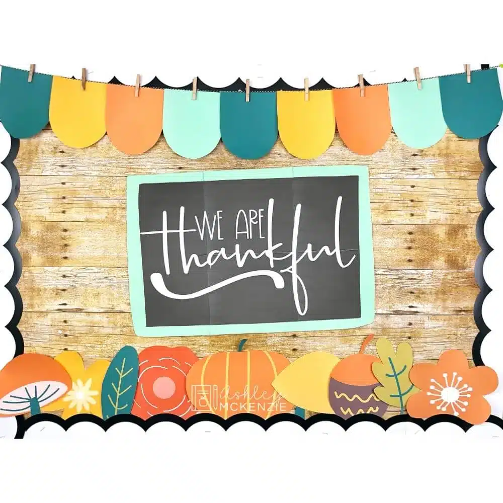 A classroom bulletin board decorated with a Thanksgiving theme featuring a chalkboard with the writing "We are thankful"