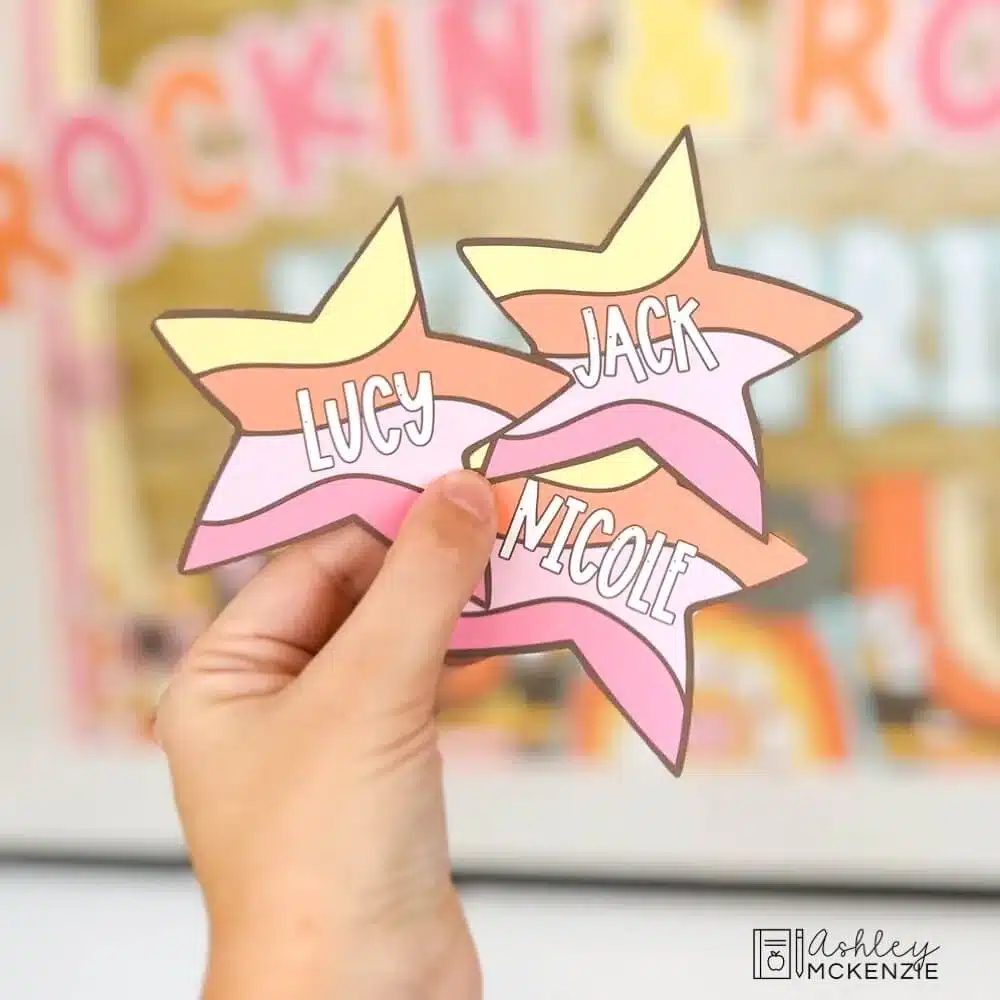 A hand holds cutouts of brightly colored stars each with student names printed on them