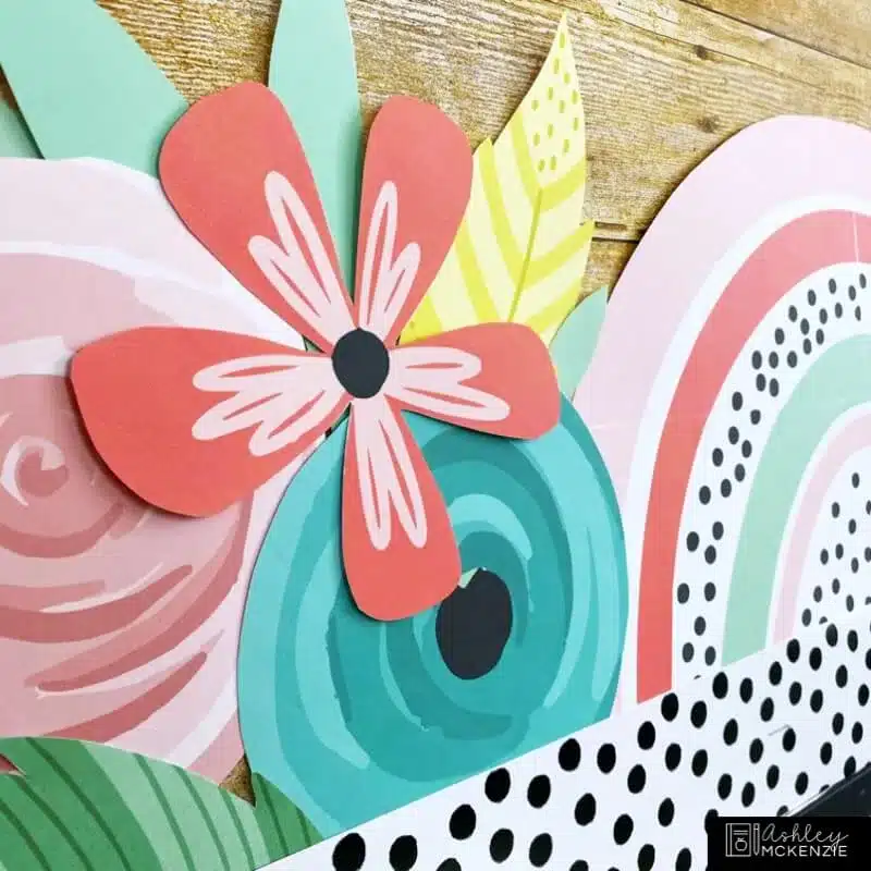 A closeup of a classroom bulletin board featuring brightly colored flower cutouts for a spring theme