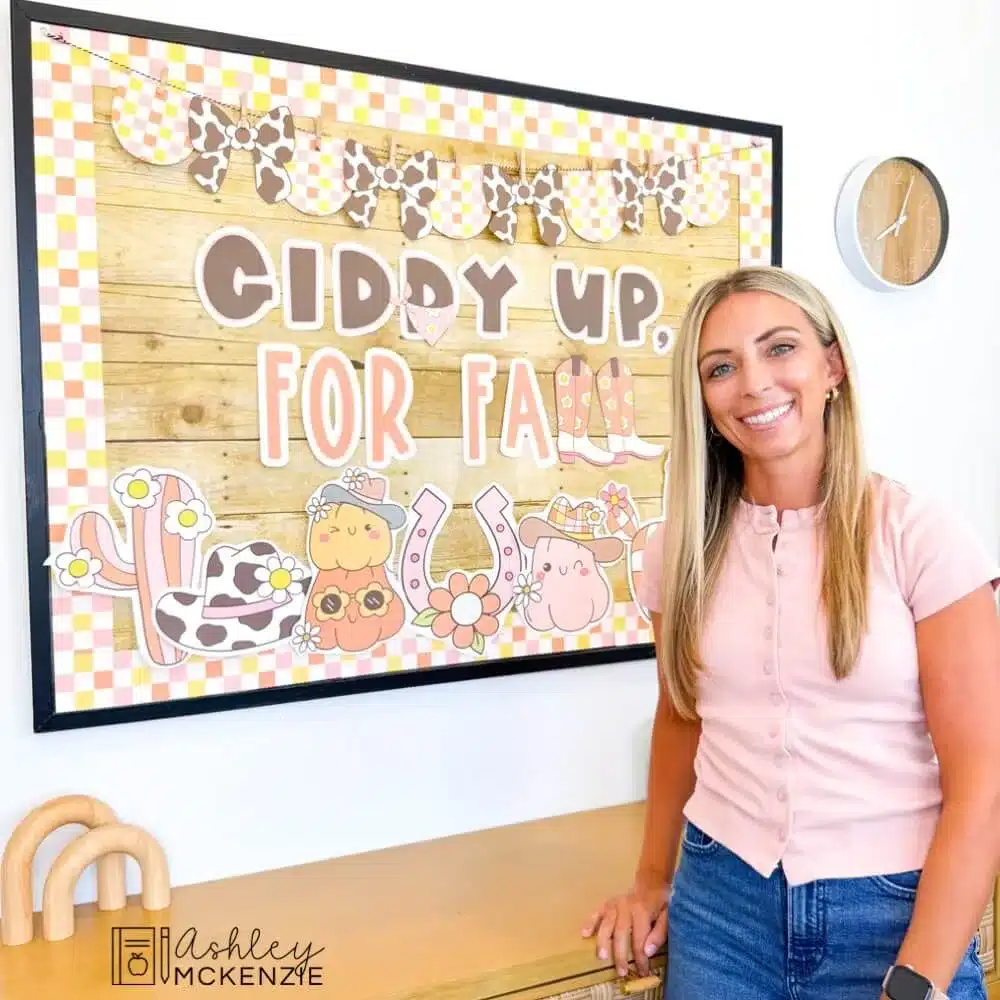 A teacher stands in front of a fall bulletin board featuring the saying "Giddy up for fall" with a Western classroom decor theme.