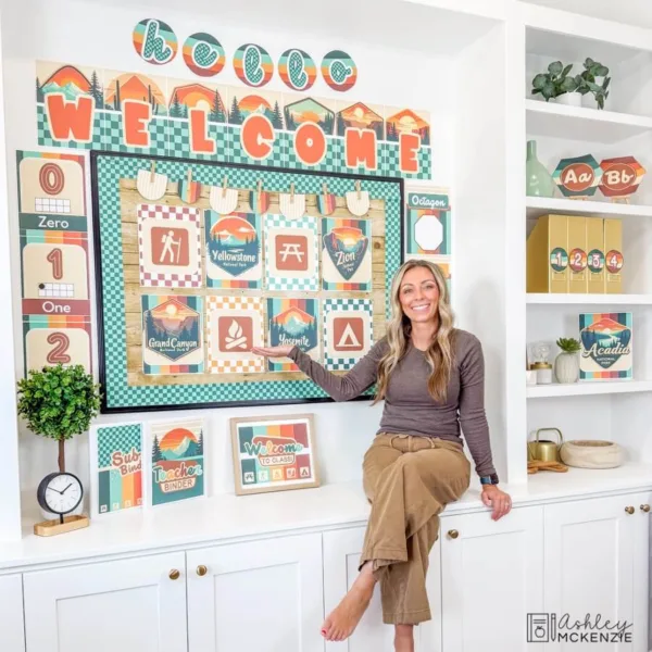 national-parks-decor-bundle-Slide7 A teacher sitting next to a National Parks bulletin board display featuring posters and welcome signs with other matching adventure theme resources